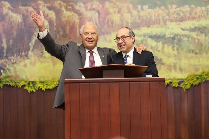 Élder Ronald A. Rasband do Quórum dos Doze Apóstolos acena para a congregação e coloca o braço ao redor de Élder Valeri V. Cordón, um Setenta Autoridade Geral e presidente da Área do Caribe, durante uma conferência especial em Santiago de los Caballeros, República Dominicana, em 13 de setembro de 2026.