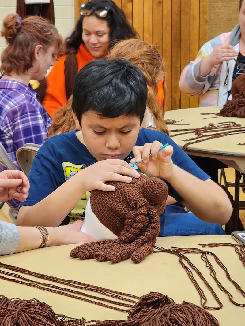 Um jovem voluntário trabalha em uma peruca que será doada a uma criança com câncer, em um evento do ServirAgora ajudando o Magic Yarn Project, na sede da Estaca Saratoga Califórnia, de 20 a 21 de outubro de 2023.