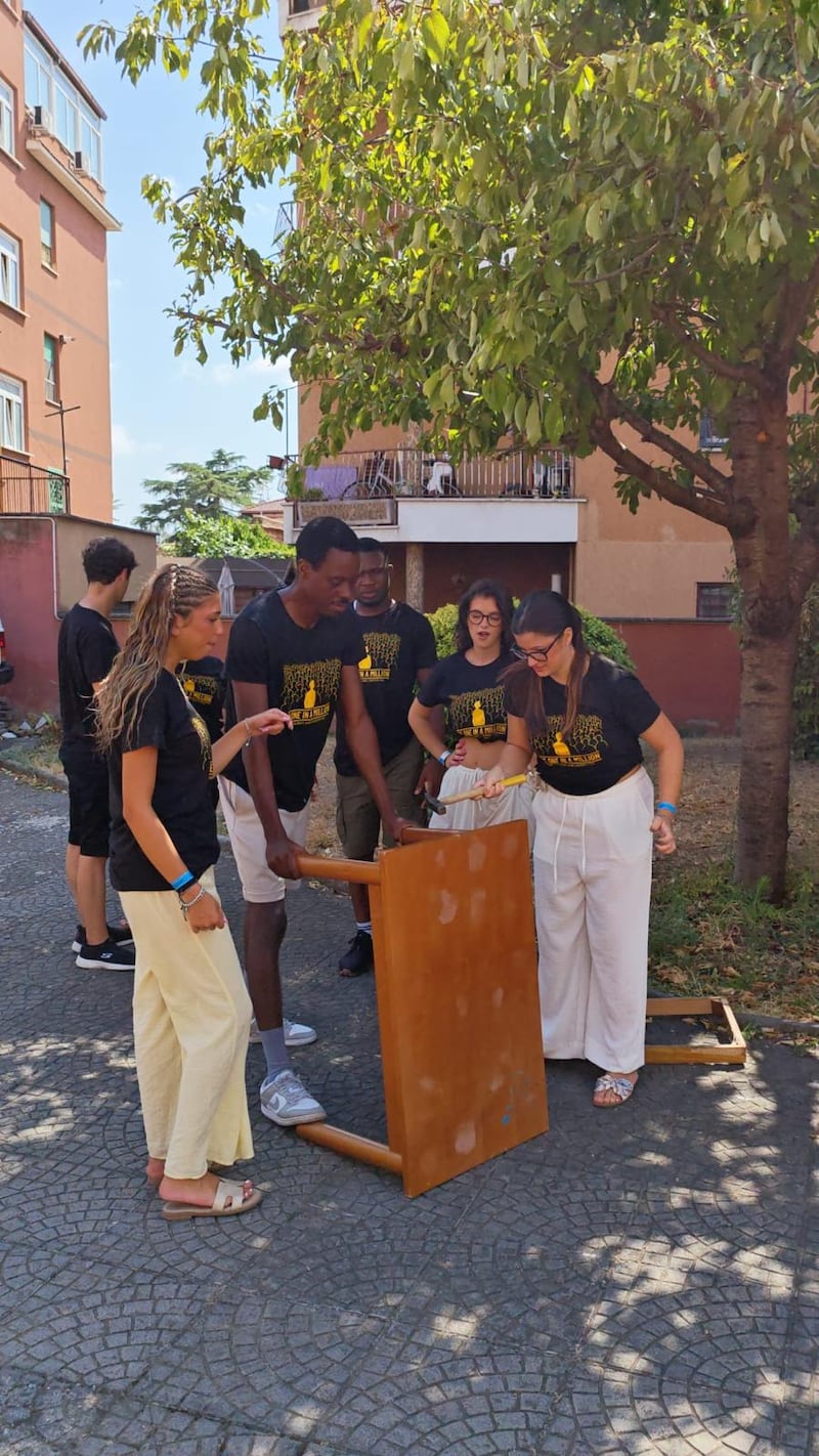 Adultos jóvenes solteros trabalham juntos para desmontar móveis durante um projeto de serviço no Casa Scalabrini 634 em Roma, Itália.