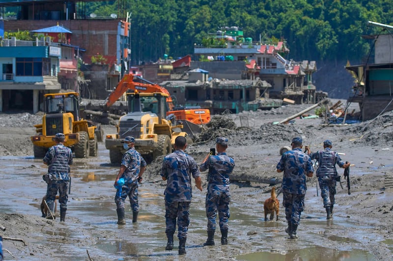 Policiais nepaleses observam enquanto as escavadeiras removem os escombros das enchentes rápidas no distrito de Nuwakot, no Nepal, quinta-feira, 27 de agosto de 2026.