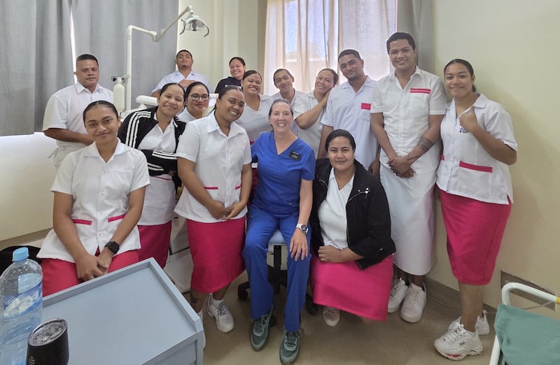 Kathleen Young, em azul, sorri com seus estudantes de odontologia na clínica do Hospital Viola em Nuku'alofa, Tonga, em março de 2026.