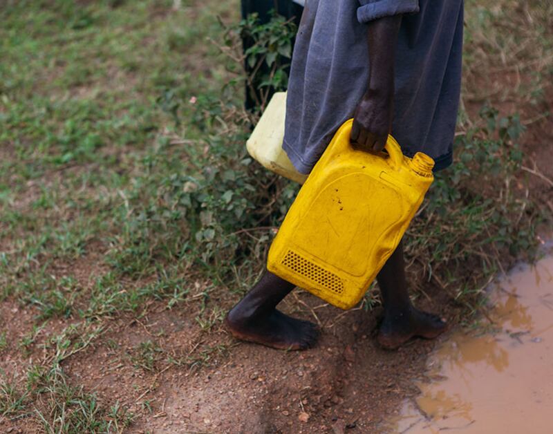 Peter e sua família enchem recipientes com água de uma nascente no distrito de Gicumbi, Ruanda. A Igreja de Jesus Cristo dos Santos dos Últimos Dias e a Water for People estão trabalhando com o governo de Ruanda para instalar mais fontes de água na área ainda em 2023.