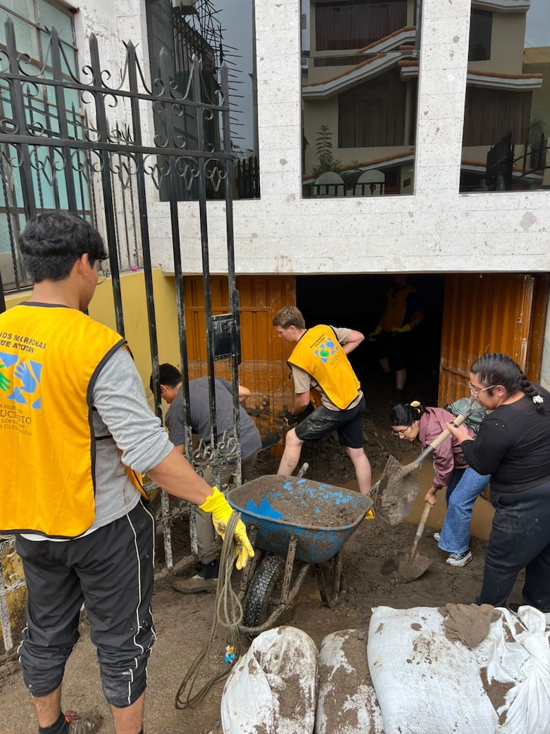 Voluntários de serviço de A Igreja de Jesus Cristo dos Santos dos Últimos Dias reúnem-se para remover lama das casas afetadas por enchentes de Arequipa, Peru. Os deslizamentos de terra começaram após chuvas torrenciais em 19 de fevereiro de 2026.