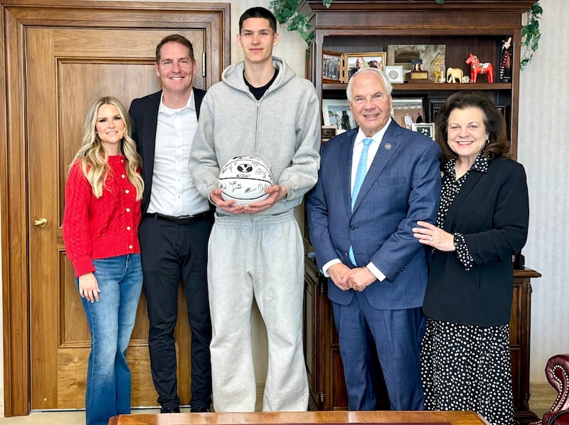 O Élder Ronald A. Rasband do Quórum dos Doze Apóstolos e sua esposa, Irmã Melanie Rasband, posam para uma foto com o armador dos Brooklyn Nets, Egor Dëmin, no centro, e LaRee e Travis Hansen, diretor atlético associado sênior da BYU, no Edifício da Administração da Igreja em Salt Lake City, Utah, no dia 30 de janeiro de 2026.