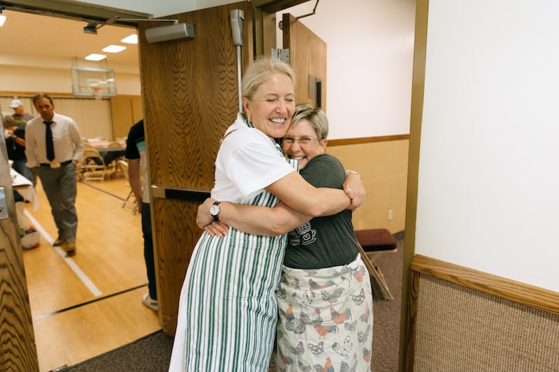 Membros da Igreja se abraçam em um templo em Spokane enquanto servem refeições aos evacuados no domingo, 2 de agosto de 2026.