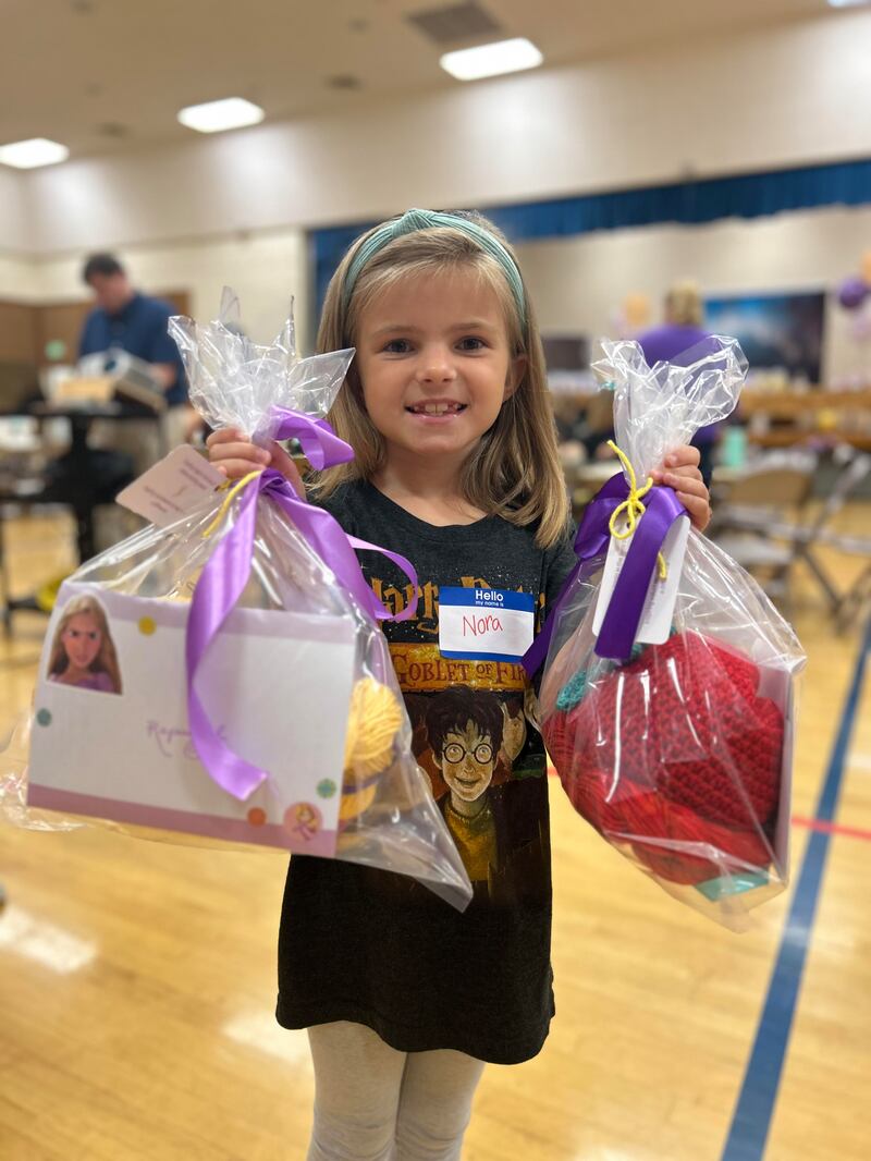 Uma pequena voluntária mostra sacolas de presentes com perucas prontas, no evento do Magic Yarn Project do ServirAgora, na sede da Estaca Saratoga Califórnia, de 20 a 21 de outubro de 2023.