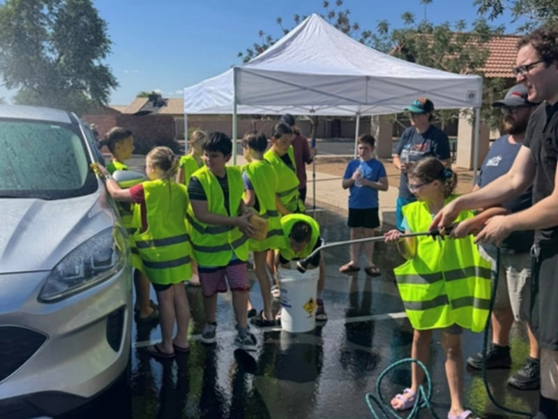 Crianças lavam um carro durante a lavagem de carro gratuita e campanha de arrecadação de brinquedos promovida pela organização da Primária da Estaca Peralta Trail Arizona, em Mesa, Arizona, no dia 11 de setembro de 2025.