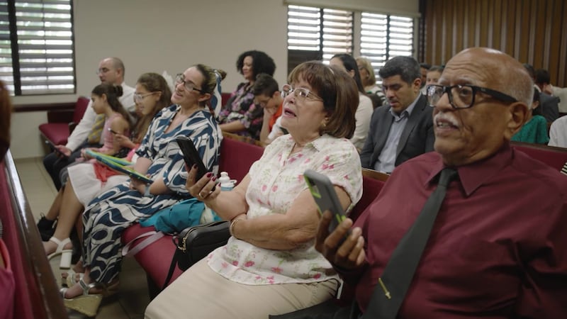 Membros da Igreja em Porto Rico cantam usando seus telefones durante sua reunião de sacramento.