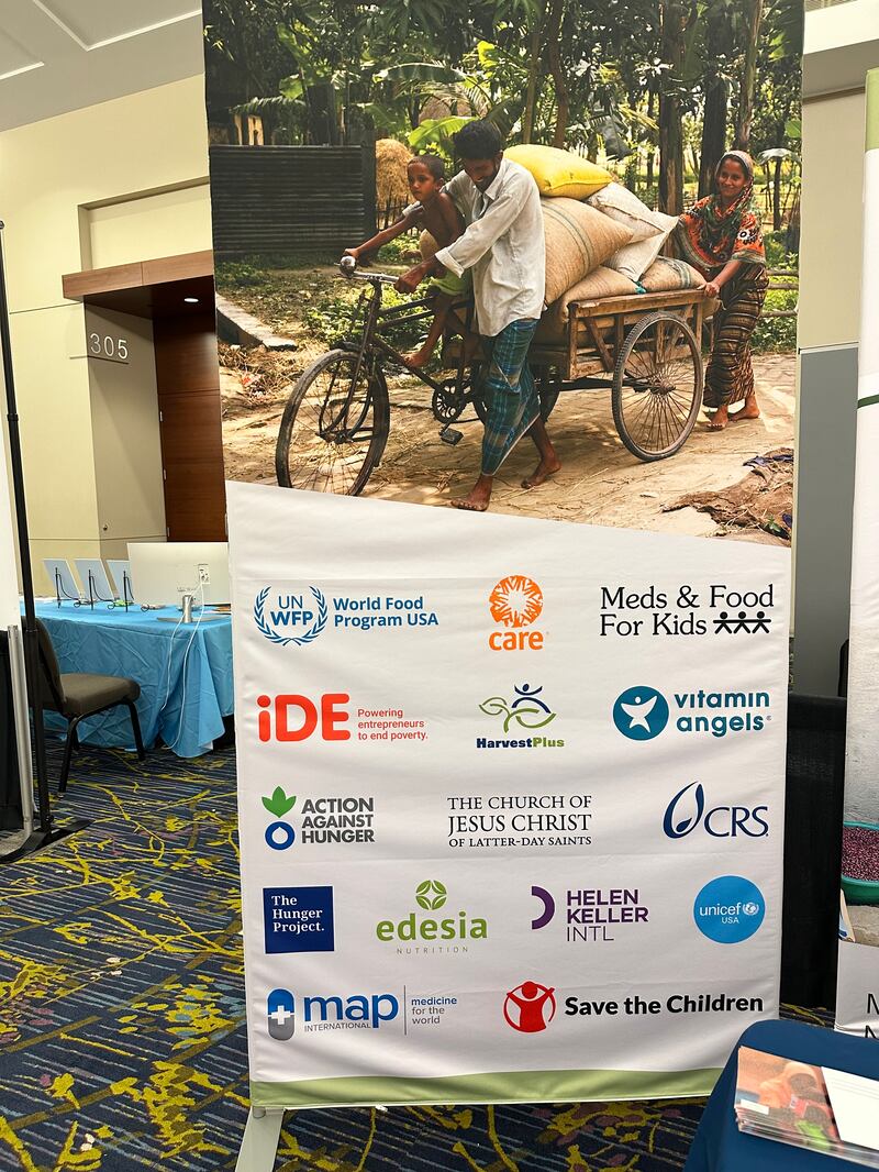 Um banner em um estande informativo da Igreja exibe os nomes de organizações globais sem fins lucrativos colaborando para ajudar os esforços de nutrição infantil em todo o mundo no Diálogo Internacional Borlaug do Prêmio Mundial da Alimentação, em Des Moines, Iowa, de 28 a 31 de outubro de 2024.