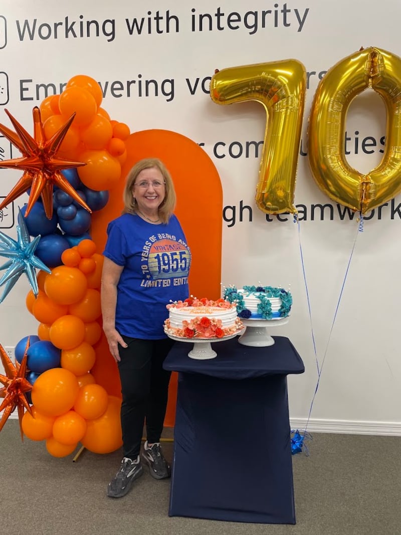 Gwynne Fullmer posa para uma foto com bolos de aniversário e balões enquanto se voluntaria no Midwest Food Bank de Gilbert, Arizona, em 18 de outubro de 2025, para celebrar seu 70º aniversário.
