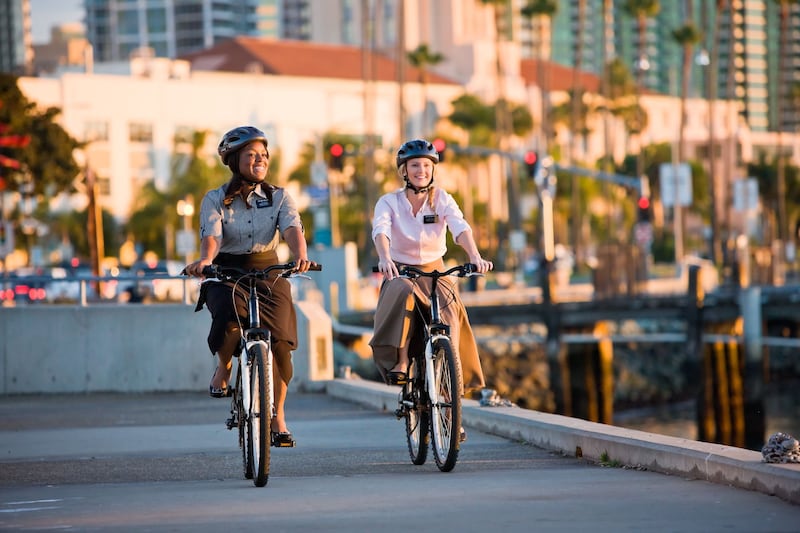 Duas missionárias mulheres usando capacetes e andando de bicicleta.
