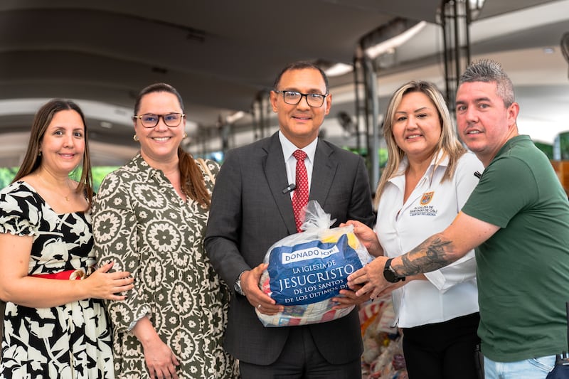 Élder Harold Truque, um Setenta Autoridade Geral de Cali, Colômbia, ao centro; fica ao lado de autoridades do escritório do prefeito de Cali, apresentando a doação da Igreja de 1.000 kits de alimentos em benefício das vítimas do terremoto em agosto de 2026.