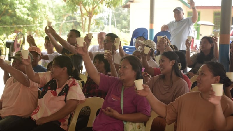 Community members raise their cups in celebration as they taste clean water in the Philippines on April 23, 2026.
