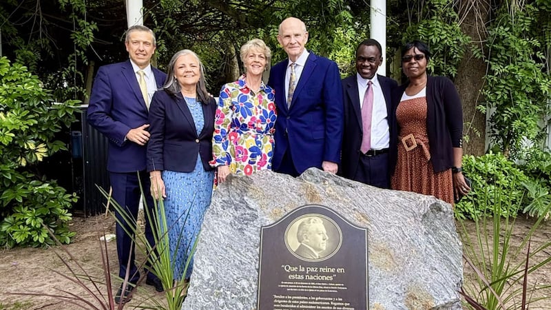 No meio, Elder Dale G. Renlund do Quórum dos Doze Apóstolos e sua esposa, Sister Ruth Renlund; à direita, Elder Edward Dube da Presidência dos Setenta e sua esposa, Sister Naume Dube; e Elder Joaquín E. Costa, Setenta Autoridade Geral e presidente da Área América do Sul Sul, com sua esposa, Sister Renée Costa, estão atrás de uma placa comemorativa marcando a dedicação da América do Sul para a pregação do evangelho. A foto foi tirada em Buenos Aires, Argentina, em 16 de novembro de 2025.