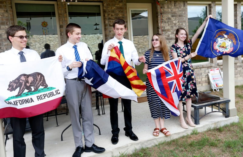 Joshua, Jonathan, Joseph, Nataleigh e Cathryn Faylor seguram bandeiras de suas designações missionárias em sua casa em San Antonio, no domingo, dia 20 de junho de 2021.