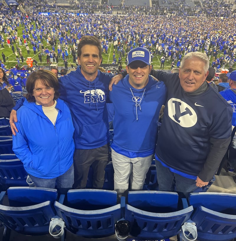 Shawna Edwards — compositora de "The Miracle" (O Milagre), uma nova adição a Hymns for Home and Church — posa com seu marido, John, e dois filhos em um jogo de futebol americano de Brigham Young durante o Outono de 2024.