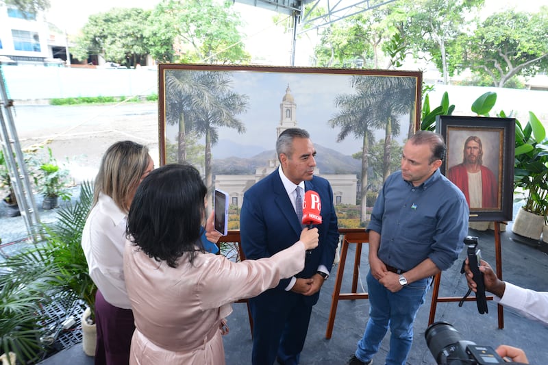Representantes da mídia entrevistando o Élder Jorge T. Becerra com microfones.