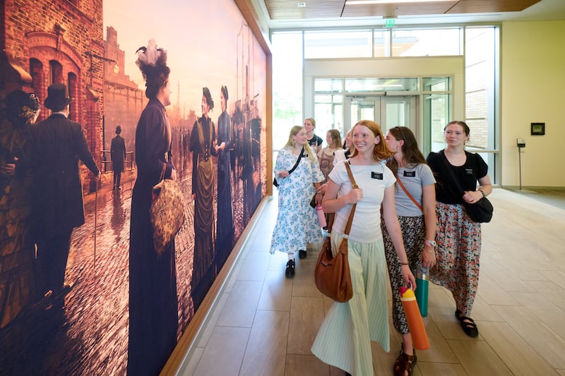 Missionárias se aproximam de um novo mural retratando as primeiras missionárias solteiras desta dispensação no Centro de Treinamento de Missionários de Provo, Provo, Utah, 19 de junho de 2026.