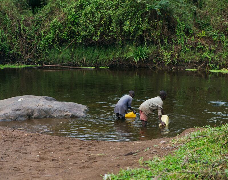 Peter e sua família enchem recipientes com água de uma nascente, no distrito de Gicumbi, Ruanda. A Igreja de Jesus Cristo dos Santos dos Últimos Dias e a Water for People estão trabalhando com o governo de Ruanda para instalar mais fontes de água na área ainda em 2023.