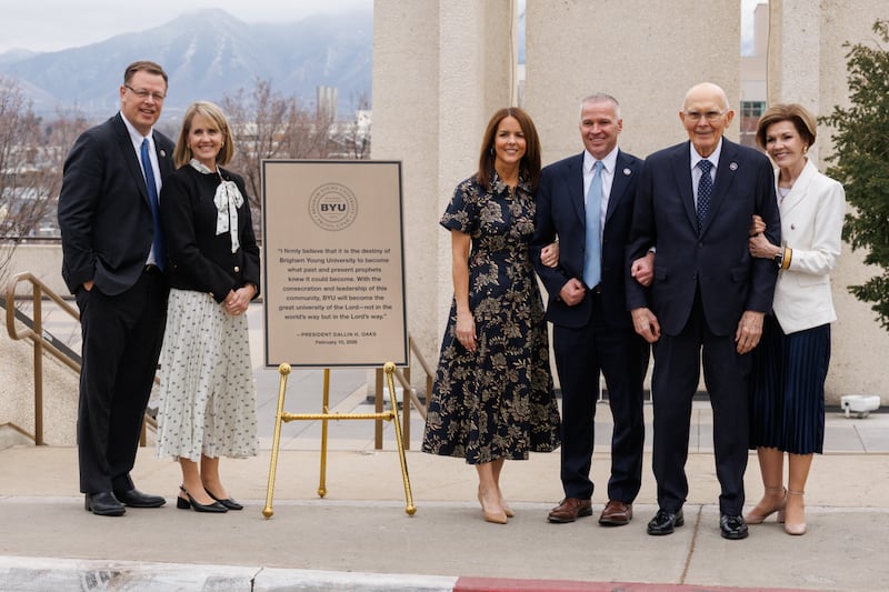 O Presidente Dallin H. Oaks, a irmã Kristen M. Oaks, o Presidente da BYU, C. Shane Reese, a irmã Wendy Reese, Elder Clark G. Gilbert e a irmã Christine Gilbert perto da Torre do Sino Carillon junto a uma nova placa com uma citação do Presidente Oaks que será colocada na base da torre em Provo, Utah, em 10 de fevereiro de 2026.