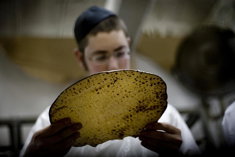 Um homem judeu ultraortodoxo examina uma Matza, um pão ázimo tradicional feito à mão para a Páscoa.