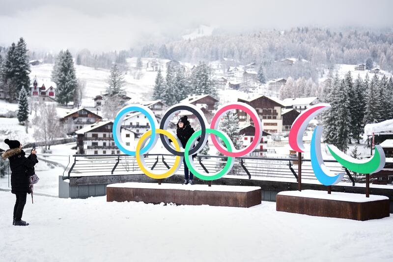 Pessoas tiram fotos em frente aos anéis das Olimpíadas de Inverno de Milão Cortina e crescentes das Paralimpíadas, em Cortina D'Ampezzo, em 20 de novembro de 2025.