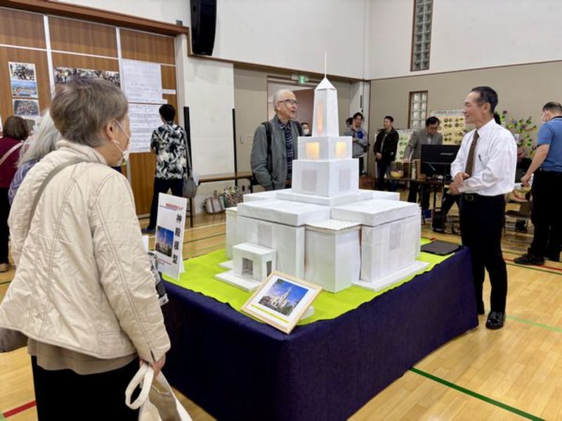 Indivíduos visualizam um modelo de papel do futuro Templo de Osaka Japão exibido em uma feira de história da família de Kyoto, Japão, 25 de outubro de 2025.