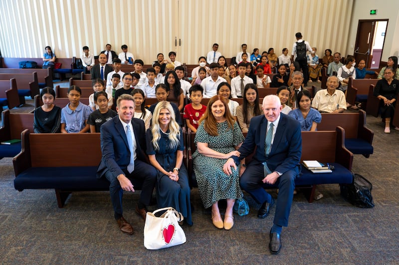 O presidente geral dos Rapazes, Timothy L. Farnes, à esquerda, sua esposa, irmã Linsey Farnes, a irmã Terri Johnson e seu marido, Élder Kelly R. Johnson, um Setenta Autoridade Geral e presidente da Área Ásia, tiram uma foto com os jovens no Camboja depois do devocional em maio de 2026.