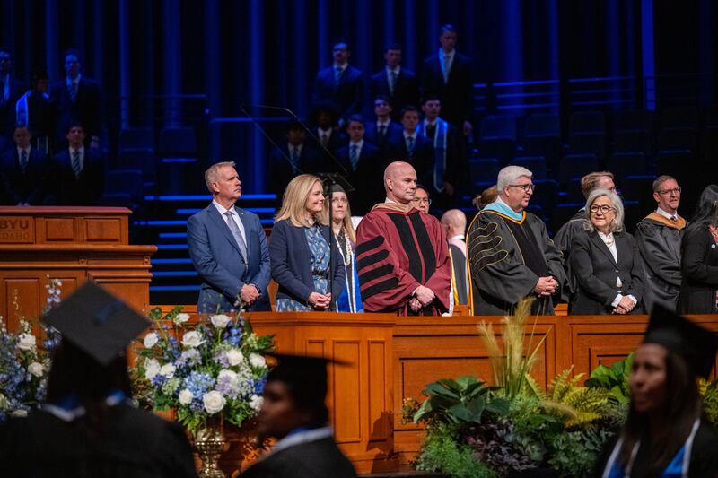 Da direita: irmã Filomena Teixeira, Elder José L. Teixeira, o presidente da BYU–Idaho Alvin F. Meredith III e a irmã Jennifer Meredith ficam em pé enquanto os formandos entram no auditório do BYU–I Center para a formatura na sexta-feira, 10 de abril de 2026, de Rexburg, Idaho.
