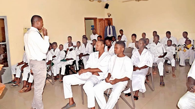 Candidatos ao batismo vestidos de branco aguardam na capela sua vez de serem batizados em uma pia batismal do lado de fora em Bamako, Mali, em 18 de abril de 2026.