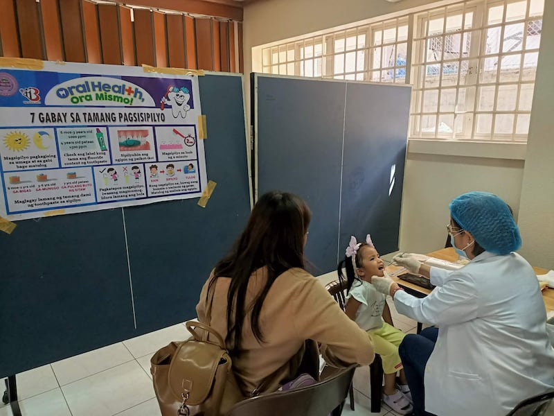 Um profissional de saúde verifica os dentes de uma menina durante uma triagem realizada no Centro de Estaca Caloocan Filipinas em 24 de janeiro de 2026.