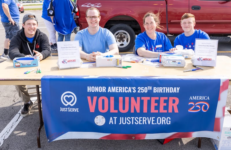 Quatro voluntários trabalham no estande America 250 e JustServe em um evento tailgate antes do jogo do Kansas City Royals em Kansas City, Missouri, quinta-feira, 9 de abril de 2026.