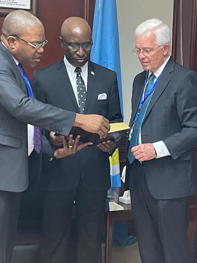 O presidente da Missão Ruanda Kigali, N. Christian Mavinga, à esquerda, e Élder Matthew L. Carpenter, Setenta Autoridade Geral e presidente da Área África Central, à direita, apresentam um exemplar encadernado em couro do Livro de Mórmon, ao primeiro-ministro de Burundi, Gervais Ndirakobuca, ao centro, em Bujumbura, Burundi, em 18 de janeiro de 2023. 