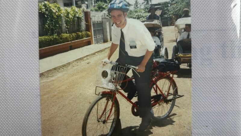 Élder David B.J. Hoare anda de bicicleta nas ruas de terra de Phnom Penh, Camboja, em 1999.