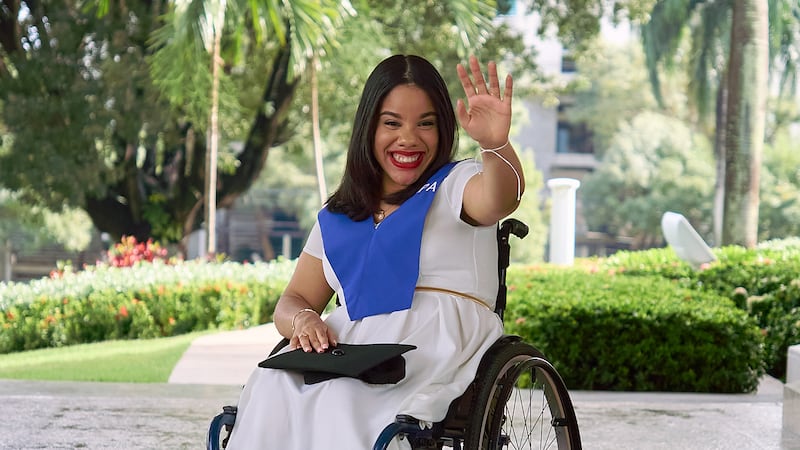 Sidney Peralta acena para a câmera após receber um diploma em psicologia industrial da Universidade Aberta para Adultos.