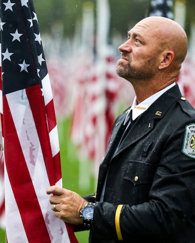 Phil Larsen, um bombeiro aposentado do Corpo de Bombeiros Voluntário de Round Hill em Washington, DC, enfrenta a chuva no 18º evento anual Healing Field, em Sandy, na quarta-feira, 11 de setembro de 2019, enquanto presta seus respeitos aos homens e mulheres que perderam sua vida durante os ataques de 11 de setembro. Larsen, um nativo de Sandy, trabalhou no Pentágono em 2001, mas estava de folga no dia do ataque.