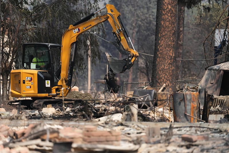 Equipes trabalham perto de várias casas queimadas após um incêndio florestal atingir a parte noroeste de Spokane, Washington, terça-feira, 4 de agosto de 2026.
