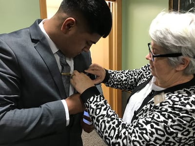 Síster Tina Dil, companheira do presidente Lindsay Dil do CTM da Nova Zelândia, ajuda um élder a colocar seu crachá de missionário pela primeira vez ao chegar ao Centro de Treinamento Missionário da Nova Zelândia em Auckland, Nova Zelândia, em 30 de junho de 2021.
