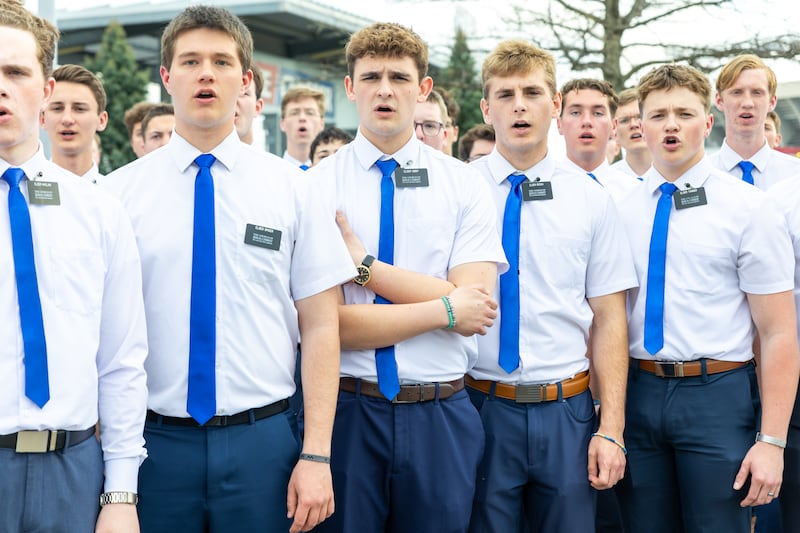 Os missionários da Missão Missouri Independence aquecem-se antes de cantar o hino nacional no jogo do Kansas City Royals, quinta-feira, 9 de abril de 2026.