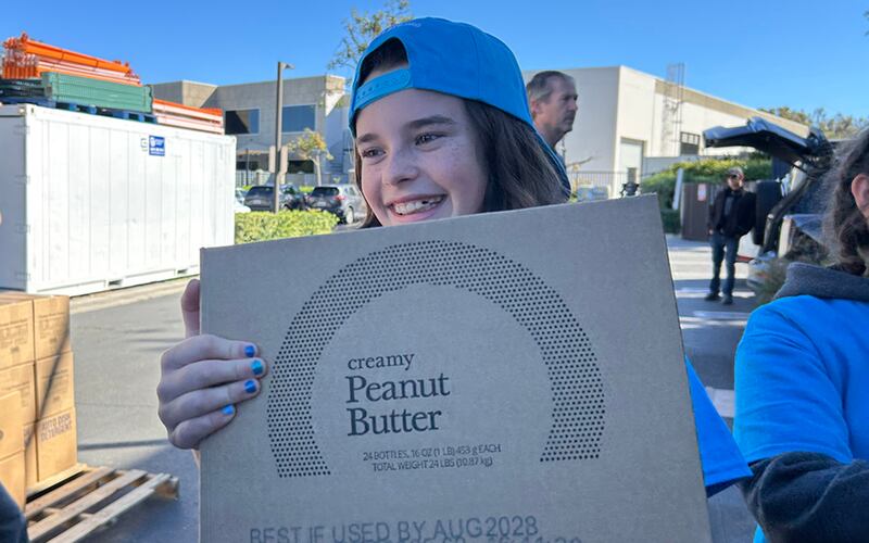 Lacey Smith, uma jovem voluntária da JustServe, ajuda a mover caixas de uma doação de alimentos da America250 de A Igreja de Jesus Cristo dos Santos dos Últimos Dias para paletes para entrega a quase uma dúzia de diferentes instituições de caridade na área de Irvine, Califórnia, no sábado, 21 de fevereiro de 2026.