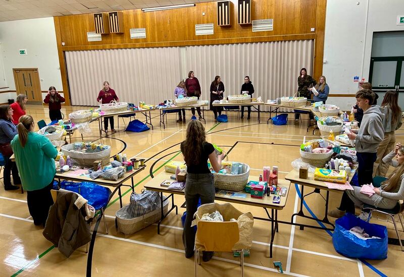 Jovens da Estaca Northampton Inglaterra montam cestas com artigos para bebês para dar a novas mães durante uma atividade de serviço em outubro de 2024.