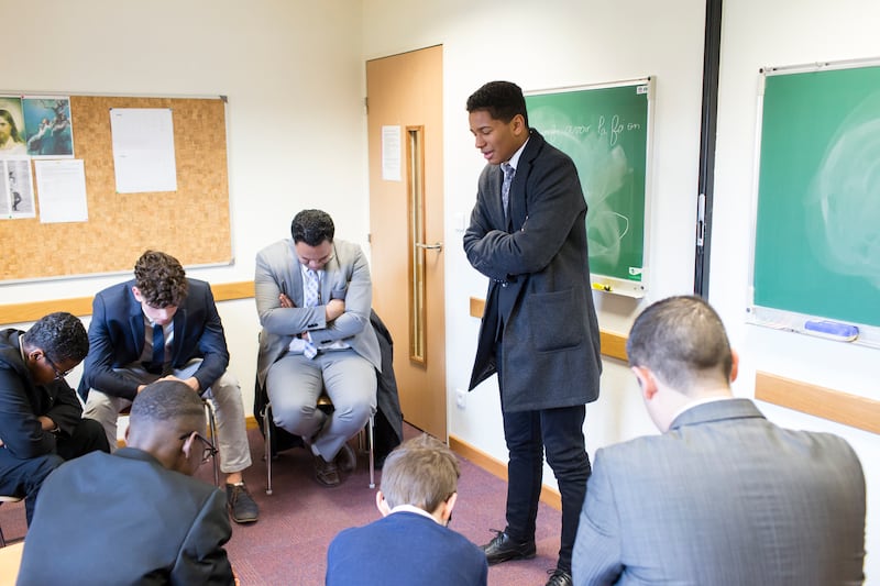 Um jovem se levanta e ora em uma aula, em Paris, França.