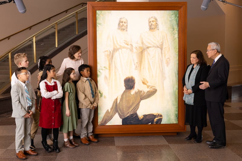 Élder Gerrit W. Gong, irmã Susan Gong, e Presidente Susan H. Porter conversam com seis crianças por um retrato da Primeira Visão no Centro de Conferências em Salt Lake City durante a gravação do Friend to Friend, lançado no domingo, 24 de maio de 2026.