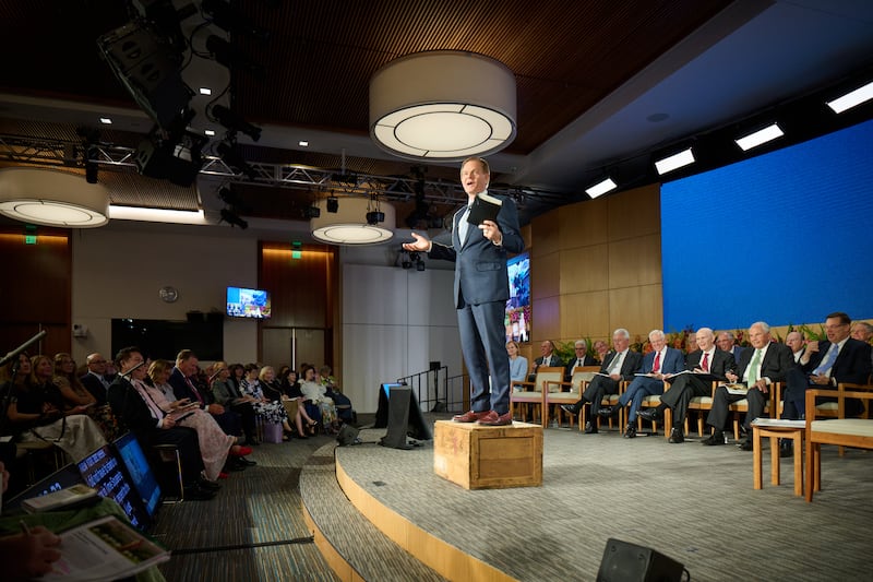 Élder Gary E. Stevenson, do Quórum dos Doze Apóstolos, fica em pé sobre uma caixa de sabão enquanto discursa no Seminário para Novos Líderes de Missão de 2026, no Centro de Treinamento Missionário de Provo, em Provo, Utah, na sexta-feira, 19 de junho de 2026.