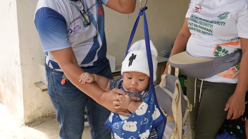 Uma criança é pesada durante um exame nutricional nas Filipinas, agosto de 2025.