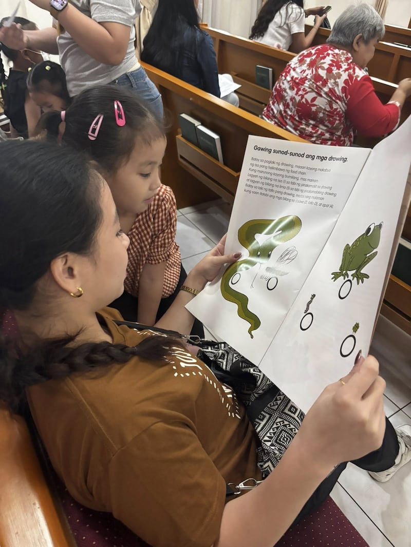 Uma mãe e uma criança leem um livro sobre nutrição durante o primeiro rastreamento do Programa de Nutrição Infantil realizado no Centro de Estaca Caloocan Filipinas em 24 de janeiro de 2026.