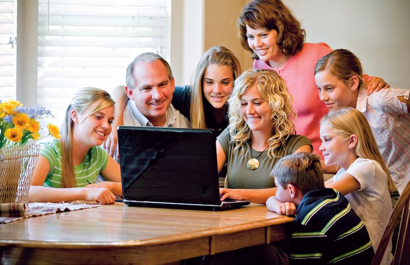 Uma família se reúne ao redor de um computador.