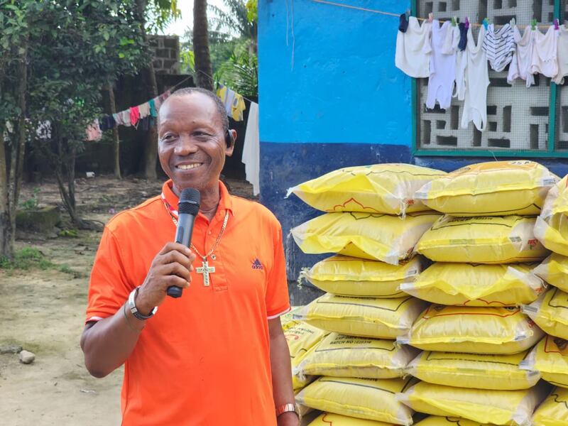 Pastor Steven Enoch ao lado de sacos de alimentos em Monróvia, Libéria, em 25 de novembro de 2025.