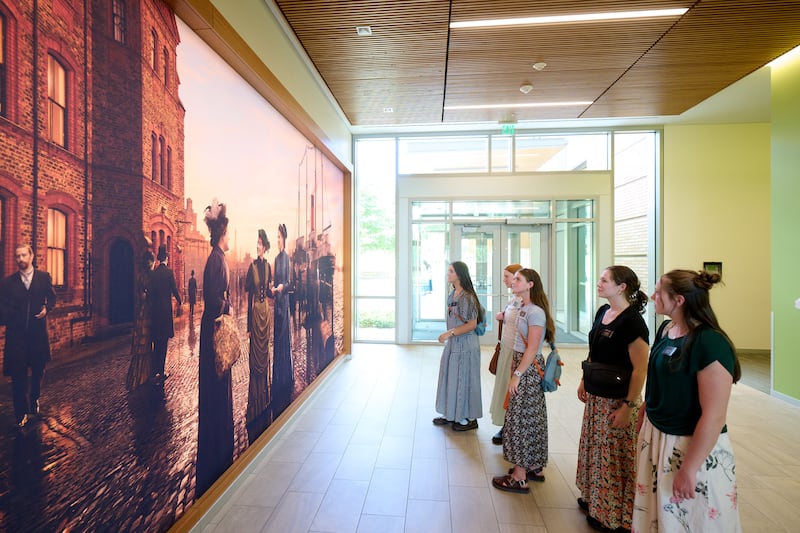 Missionárias olham para um mural que retrata as primeiras missionárias solteiras desta dispensação no Centro de Treinamento Missionário de Provo em Provo, Utah, 19 de junho de 2026.