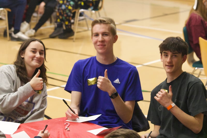 Jovens da Estaca Northampton Inglaterra escrevem cartões postais em uma mesa durante uma atividade de serviço em dezembro de 2024.